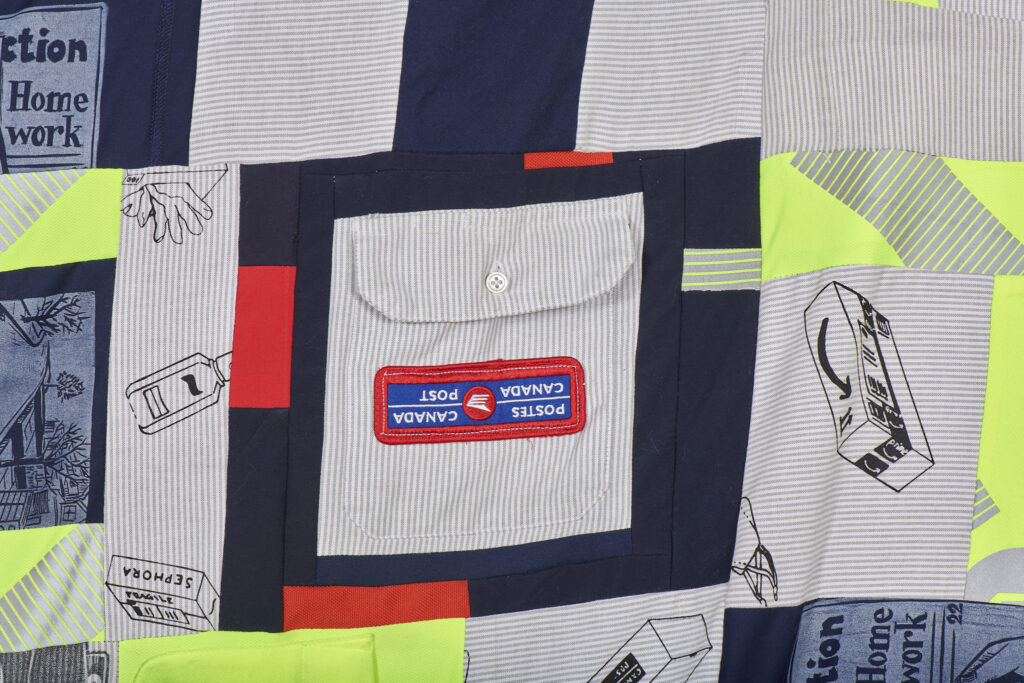 Detail of a quilt patched from pieces of Canada Post courier uniforms. Images of parcels, face masks and disposable gloves are printed on. 